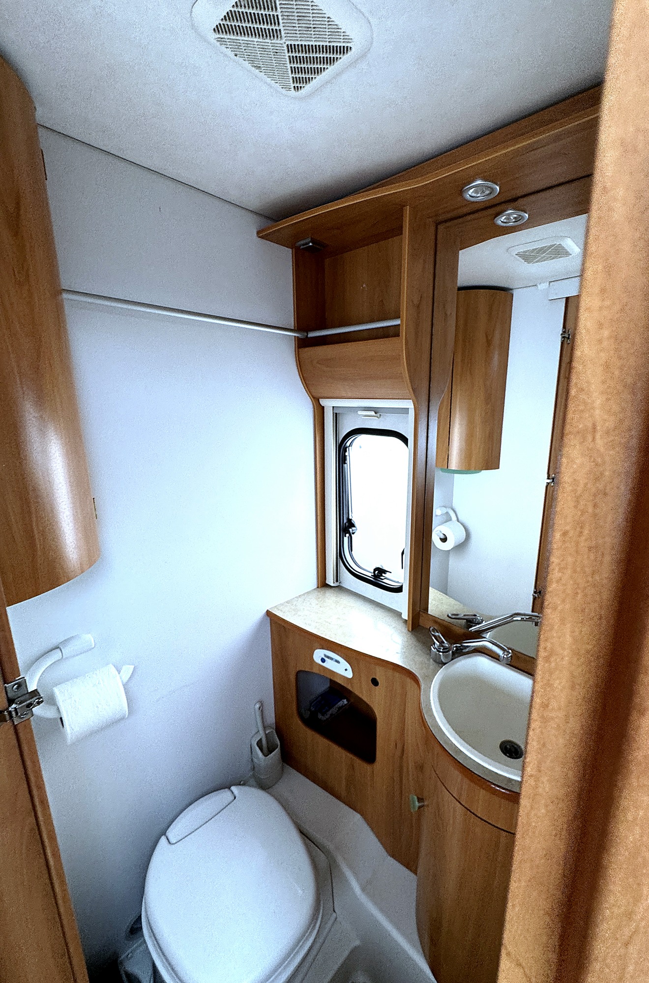 Bad mit Thetford Kassettentoilette, Waschbecken, großem Spiegelschrank und Dachhaube.